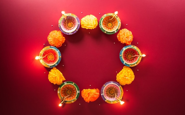 Happy Diwali Clay Diya lamps lit during Diwali Hindu festival of lights celebration Colorful traditional oil lamp diya on red background