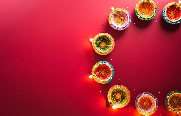 Happy Diwali Clay Diya lamps lit during Diwali Hindu festival of lights celebration Colorful traditional oil lamp diya on red background