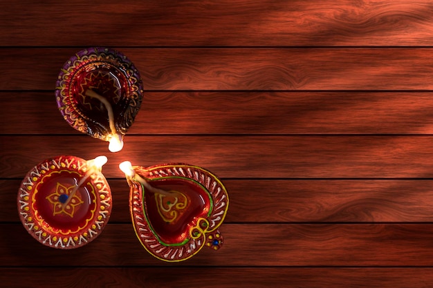 Happy Diwali Clay Diya lamps lit during Diwali on wooden background