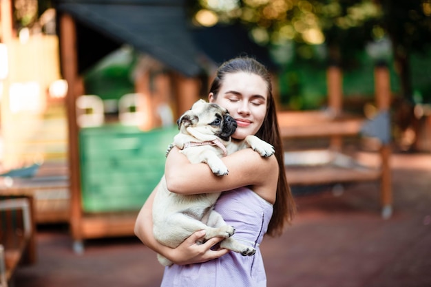 Happy dog and girl The girl is playing with a dog Young woman walking with a pug dog in summer park Portrait of a pug Portrait of a beautiful pug puppy The dog is lying on the ground