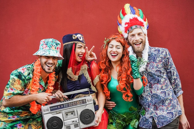 Happy dressed friends celebrating at carnival party together outdoor - Focus on faces