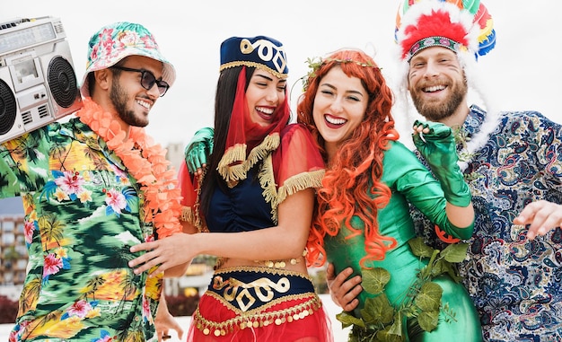 Happy dressed people celebrating at carnival party dancing together - Focus on faces