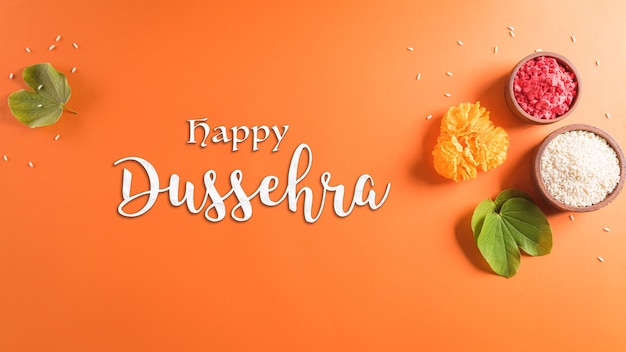 Happy Dussehra Yellow flowers green leaf and rice on orange background Dussehra Indian Festival concept