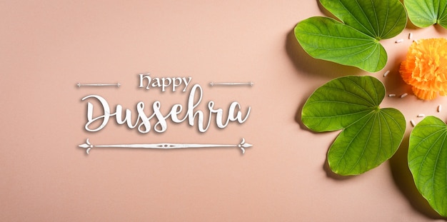 Photo happy dussehra. yellow flowers, green leaf and rice on orange pastel background