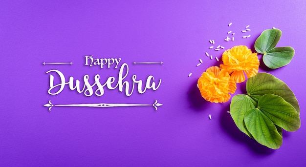 Happy Dussehra. Yellow flowers, green leaf and rice on purple pastel background