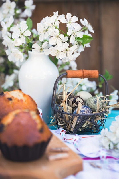 Happy easter - basket of eggs  and cupcakes on the background of cherry blossoms