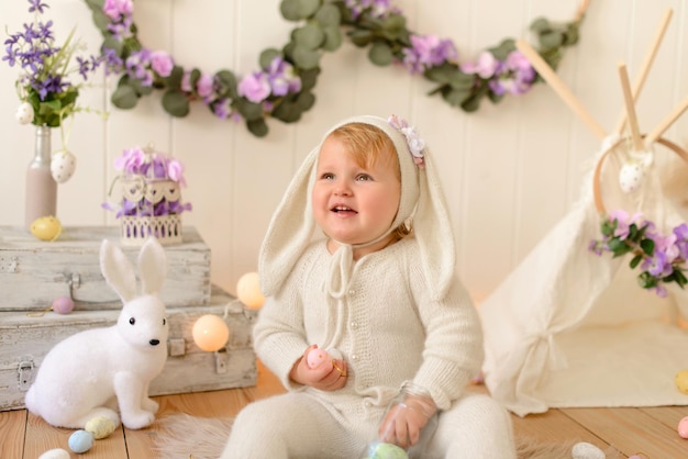 Happy easter bunny girl with colorful eggs sitting in country house and celebrating holiday