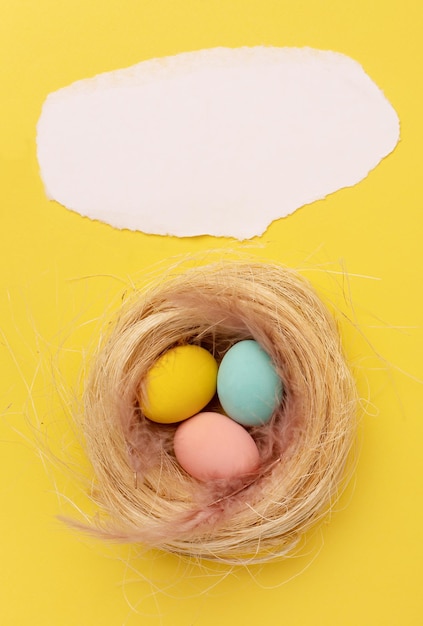 Happy Easter card colored yellow pink blue easter eggs on yellow background of a nest top view image