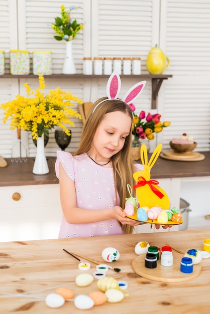 Happy Easter. The child is preparing for Easter. A girl holds a stand with Easter colored eggs..