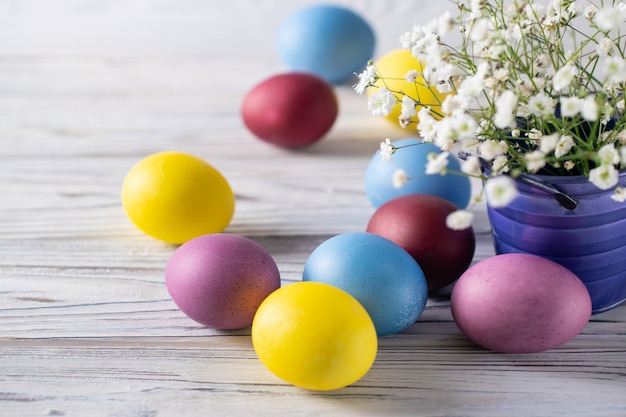 Happy easter colorful dyed eggs with spring white flowers in a bucket