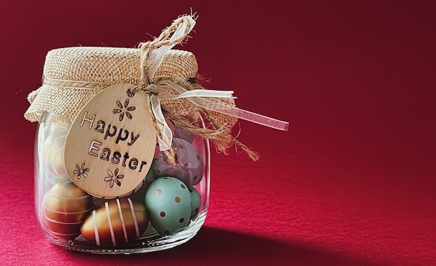 Happy Easter Colourful painted easter eggs in glass jar on red background Christian religion and holiday concept