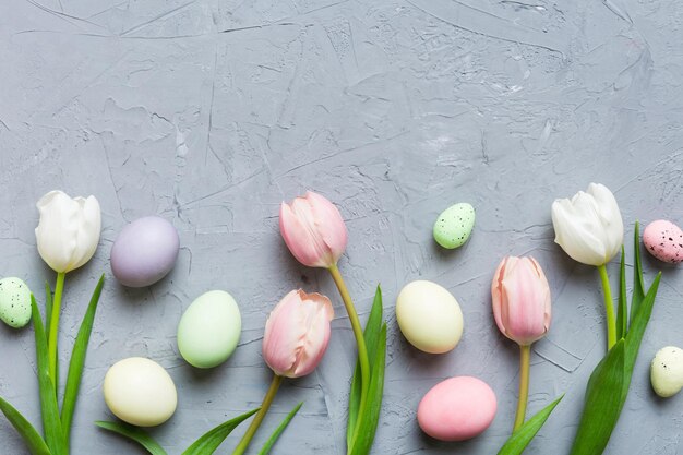 Happy Easter composition Easter eggs on colored table with yellow Tulips Natural dyed colorful eggs background top view with copy space