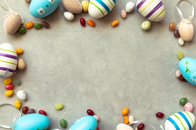 Happy Easter concept. Preparation for holiday. Easter eggs candy chocolate eggs and jellybean sweets on concrete stone grey background. Flat lay top view copy space banner.