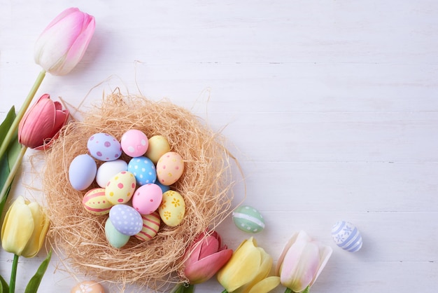 Happy Easter day eggs in nest and flower on wood background with copy space