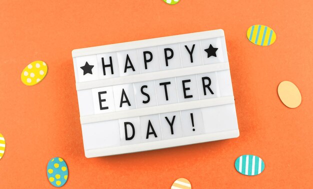 Photo happy easter day text background with greetitngs and easter eggs orange paper and flat lay photo