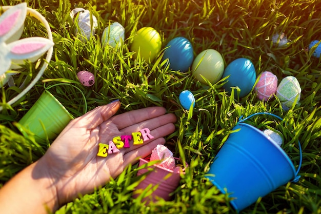 Happy Easter. Easter eggs hidden in spring grass. Writing made of wooden letters in hand