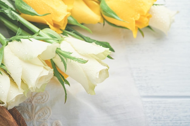 Happy Easter Easter eggs on rustic table with white and yellow roses Natural dyed colorful eggs in wooden plate and spring flowers in rustic room Toned image Easter background with copy space