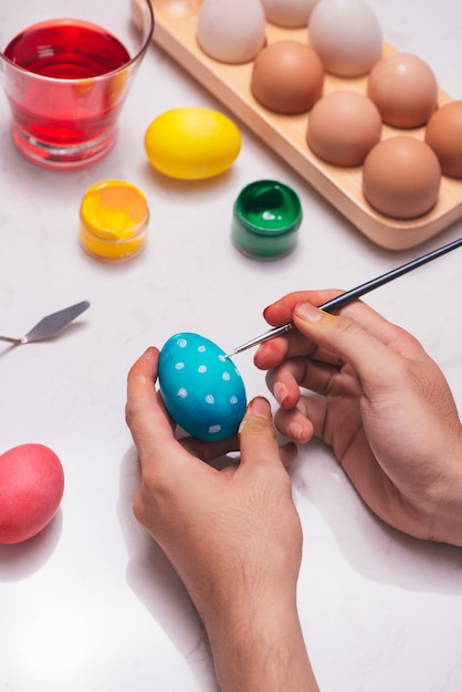 Photo happy easter! father painting easter eggs on table.