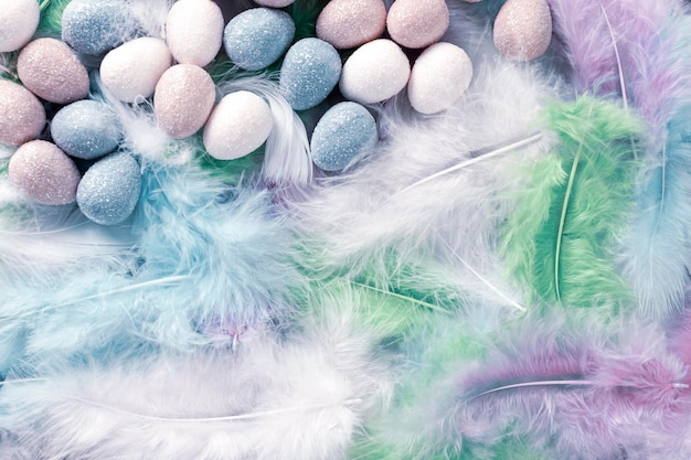 Happy Easter Holiday Decorative Easter eggs on colorful feathers background Copy space Flat lay