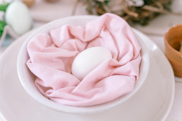 Happy easter holiday in springtime season festive home decor traditional food natural white chicken egg in pastel pink fabric in a plate on the table