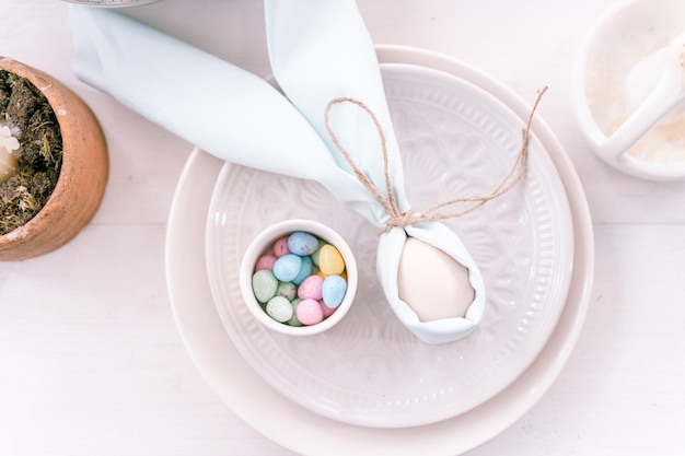 Happy easter holiday in springtime season festive home decor traditional food white beige chicken egg wrapped in pale blue cloth like rabbit or bunny ears in plate and small candy eggs on table