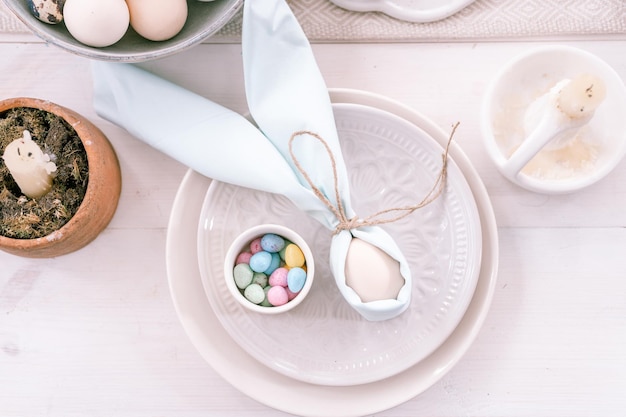 Happy easter holiday in springtime season festive home decor traditional food white beige chicken egg wrapped in pale blue cloth like rabbit or bunny ears in plate and small candy eggs on table