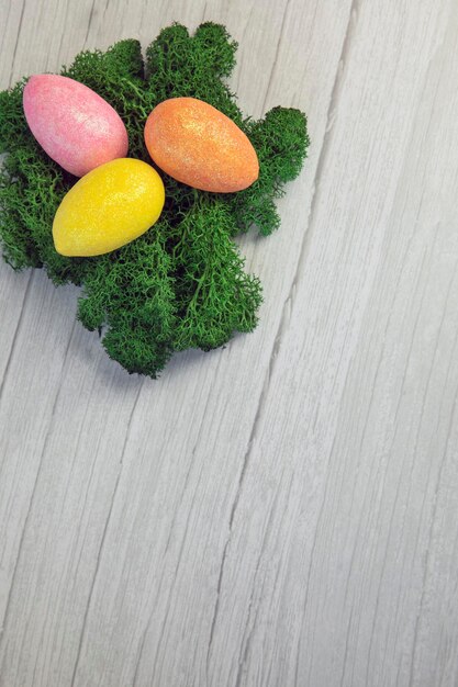 Photo happy easter holliday concept colorful easter eggs with green moss on white wooden background textur...