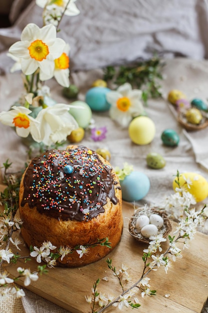 Happy Easter Homemade easter bread and natural dyed easter eggs with spring flowers on linen napkin on rustic table Traditional Easter food Top view