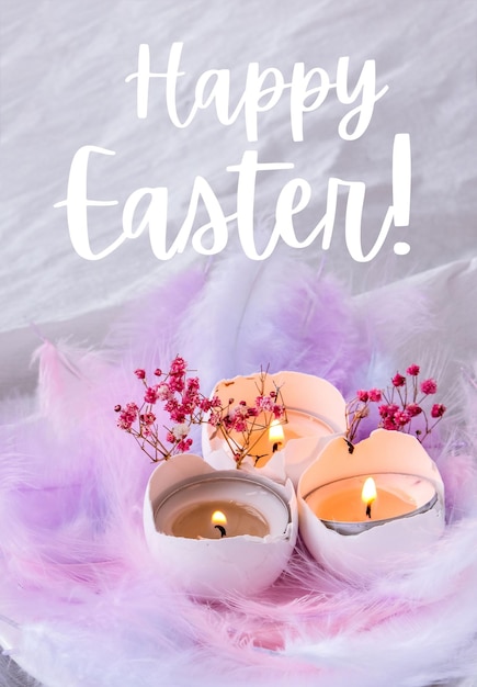 HAPPY EASTER lettering greeting card text. Composition of White egg shell with candle inside. Candle light. Bright easter decorations with bird feathers. Pastel colors.