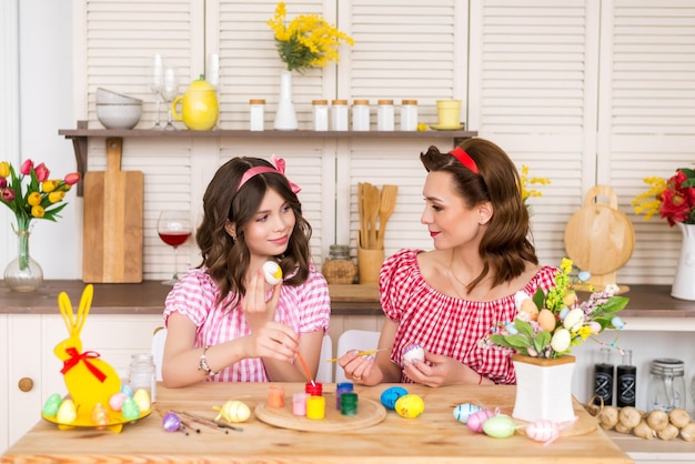 Happy easter A mother and her daughter painting Easter eggs Happy family preparing for Easter