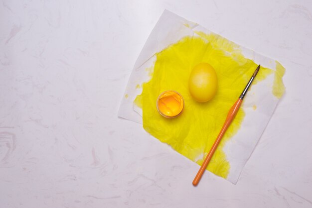 Happy Easter! Painting yellow easter eggs on table.