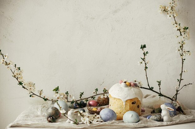 Photo happy easter stylish easter eggs cake bunnies cherry blossom on rustic table modern natural dyed eggs holiday food and spring flowers easter countryside still life