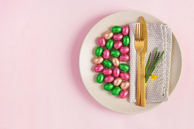 Happy Easter Table setting for Easter holiday Easter eggs flower and cutlery on pink background Top view flat lay