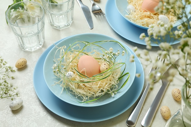 Happy Easter table setting with eggs on white textured table