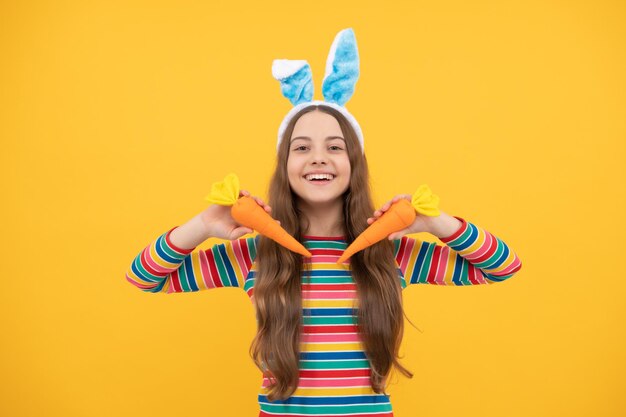 Happy easter teen girl in rabbit bunny ears holding carrot for holiday, easter holiday.