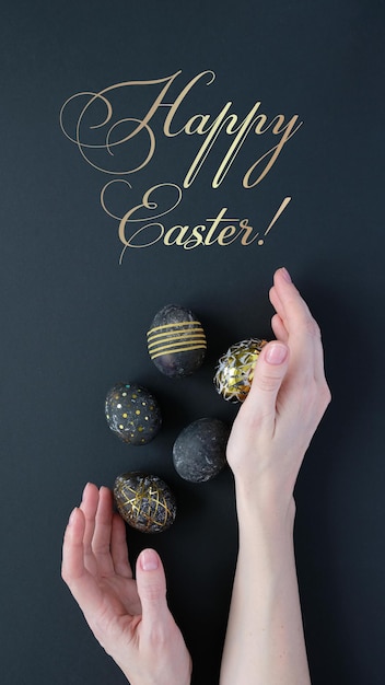 Happy Easter. Woman hands holding black easter eggs with gold pattern on black background. Luxury easter