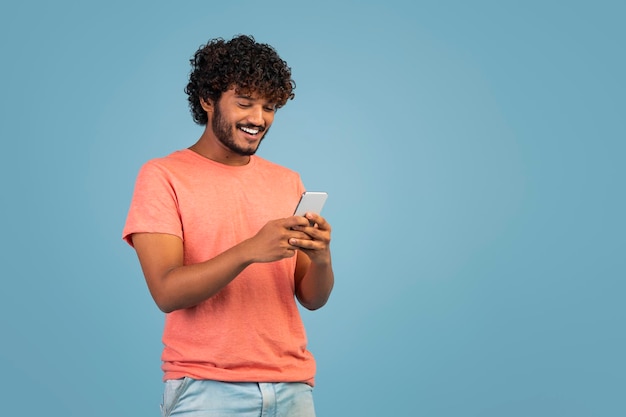 Happy eastern guy checking newest mobile app using phone