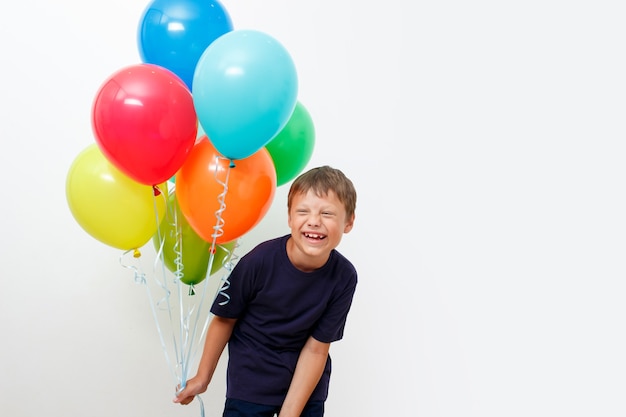 Happy eight year old boy with an armful of bright colorfull balloons celebrates birthday