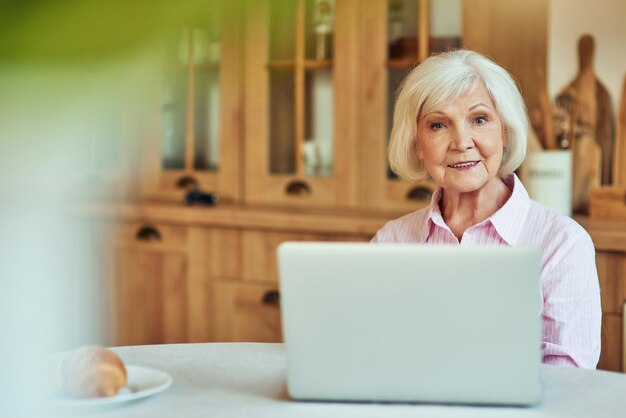 Happy elder female using computer at home