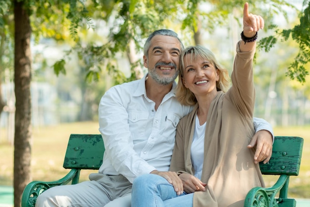 Happy elder love couple huge and smiling in romance sitting in park