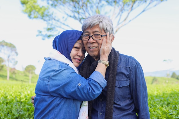 Happy elderly couple laughing at tea plantation Happy old woman holding her husband's cheek