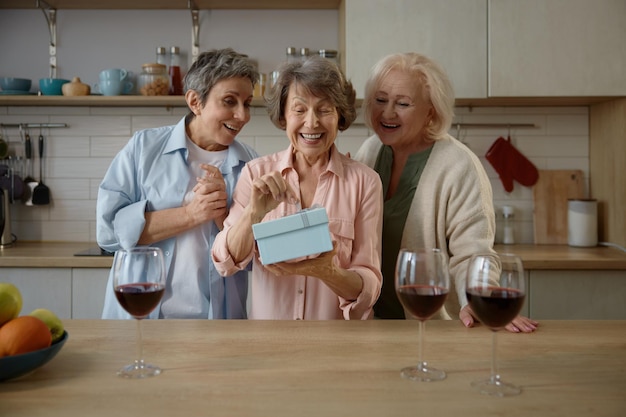 Happy elderly ladies celebrating birthday at home kitchen