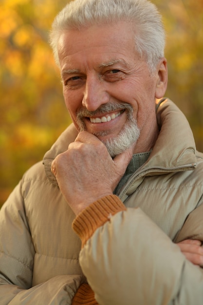 Happy elderly man enjoying in autumn park