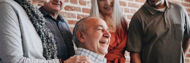 Happy elderly man on a wheelchair talking with friends