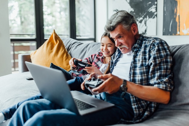 Happy elderly man with a little girl  playing game while lying at home