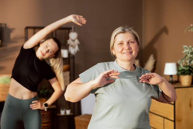 Happy elderly mother spends time with young daughter doing sport exercises stretching indoors