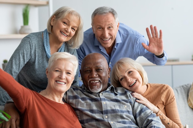 Happy elderly people taking selfie together home interior