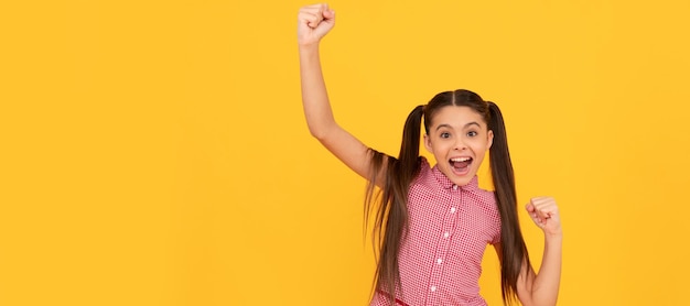 Happy enthusiastic kid make winning hand gesture screaming and celebrating yellow background joy