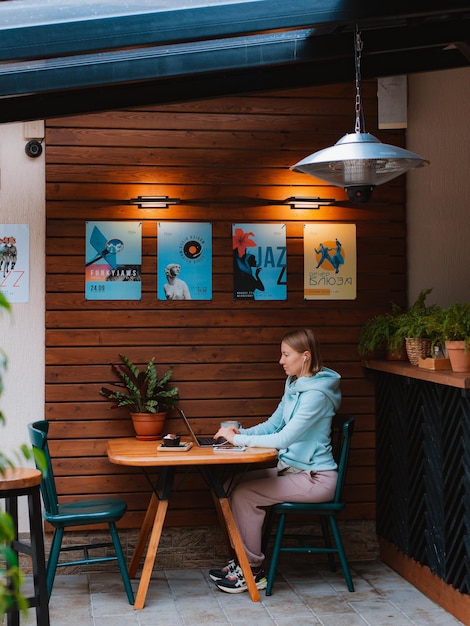 Happy entrepreneur working with a phone and laptop in a coffee shop in the street