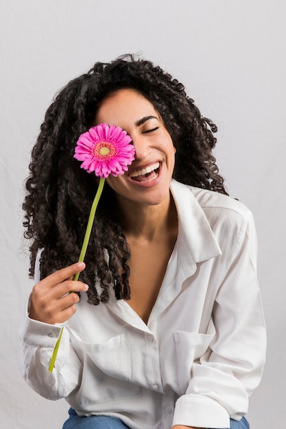 Happy ethnic woman with flower against eye